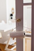 Kitchen roll on wire coathanger hung on brass doorknob