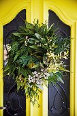 Wreath of different branches on a yellow front door