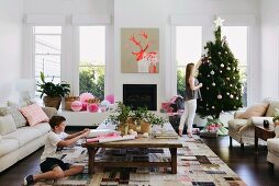 Jugendliche schmückt Weihnachtsbaum und Junge verpackt Weihanchtsgeschenk in zeitgenössischem australischem Wohnambinete