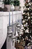 Christmas decorations in silver with a blue ribbon on a mantelpiece