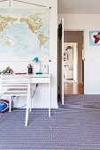 Jugendzimmer mit gestreiftem Teppichboden, weißem Schreibtisch und aufgehängter Landkarte