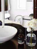 White flowers and soap dispenser in front of cosmetic mirror on vanity with traditional flair