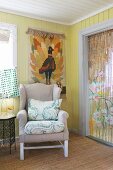Wing-back chair below tapestry on board wall and next to Oriental bead curtain