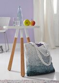 A striped crocheted shopping bag with a colour gradient next to a dip-dyed style stool