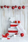 Christmas presents wrapped in red and white and red baubles against board wall