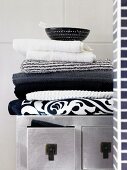 Stapel aus Handtüchern in Schwarz, Weiß und Grau auf silbernem Asia-Schränkchen