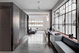 Industrial loft apartment in shades of grey with concrete floor and factory windows