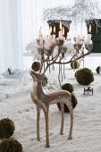 Silver candelabra in shape of a stag with lit candles on antlers stodd amongst artificial snow