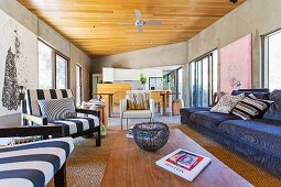 Offener Loungebereich mit Blick auf Essbereich und Küchenzeile in Architektenhaus mit Betonwänden, Holzdecke und modernen Kunstbildern
