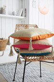 Stacked cushions with hand-sewn covers and tassels on wicker chair