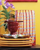 Stacked crockery in front of patterned glass vase
