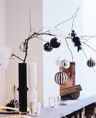 Kahler Zweig in schwarzer Vase mit eleganten Christbaumkugeln und Dekovögeln