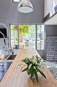 Modern stainless steel kitchen with industrial lamps and windows