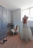 Tailors' dummy wearing underskirt in front of dressing table and easy chair