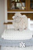 Plüsch-Schaf auf einem Stapel Wolldecken