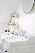 Washstand with white base unit below sloping ceiling and shelves and basket mounted on wall