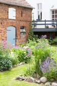 Flowerbeds edged with stones in cottage garden outside barn