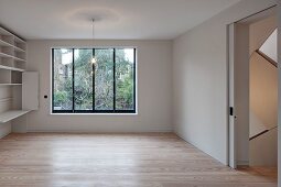 Leerer minimalistischer Wohnraum mit Einbau-Schrankwand, Parkettboden und Schiebetür