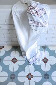Towel hung over edge of bathtub on grey-blue cement floor tiles