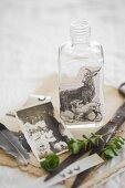 Still-life arrangement of vintage family photo and bottle decorated with vintage picture of goats