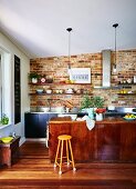 Küche mit Backsteinwand, Kücheninsel und Holzboden