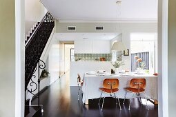Classic wooden chairs at a set dining table in front of the kitchen area, to the side of the stairs