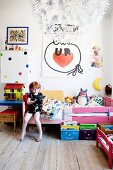 Girl wearing headphones sitting on bed in colourful bedroom