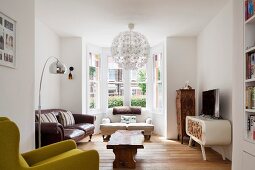 Bay window, spherical pendant lamp, wooden coffee table and antique sofas in eclectic interior