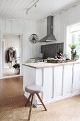 Kitchen counter and stools in country-house kitchen with white wood-clad walls and cork flooring