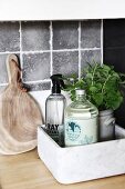 Bottled and potted herbs in marble box next to chopping board on kitchen worksurface