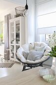 Cushions on comfortable papasan chair in bright interior with Scandinavian ambiance