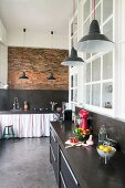 Black kitchen counters in loft apartment with brick wall and polished concrete floor