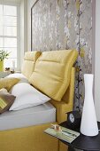 A yellow boxspring bed against framed Japanese-style wallpaper
