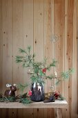 Festively decorated pine branches in glass jar of bark on rustic bench