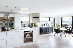 Dining area, black chairs and panoramic window in white, open-plan designer kitchen