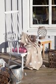 Star-patterned blanket on comfortable white rocking chair on wooden terrace