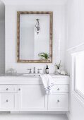 Weisser Waschtisch mit Marmorplatte und Wandspiegel an gefliester Wand
