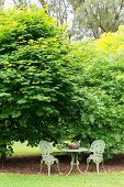 Romantischer Gartenplatz für zwei vor grünen Büschen