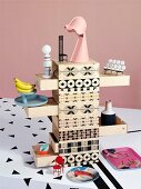 Miniature accessories on wooden chest of drawers printed with mixture of patterns