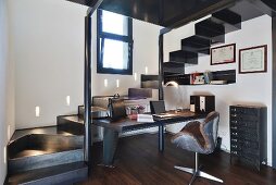 Schreibtischplatz unter schwarzem Treppenaufgang