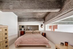 Ribbon window, ethnic art and ribbed concrete ceiling in bedroom