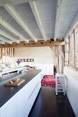 Elegant kitchen island in converted barn with rustic wood-beamed ceiling