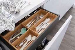 An open drawer with a wooden cutlery holder