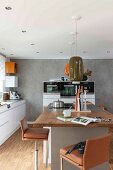 Bar stools with brown leather covers around a kitchen island with a pendant lamp with a retro ceramic shade in a modern kitchen