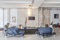 Beanbags on pallets on castors in lounge of loft apartment with brick wall and concrete floor
