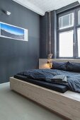 Modern wooden bed and photo art on black wall in minimalist bedroom