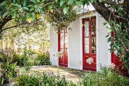 Blick durch Bäume auf Haus mit roten Türen