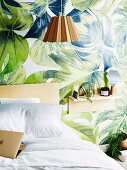 Jungle-patterned wallpaper and bedside shelf in bedroom
