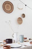 Wooden bowls on set table and decorations on wall made from natural materials
