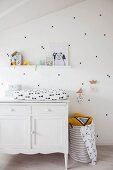 Changing mat on top of white cabinet against white wall decorated with black stickers